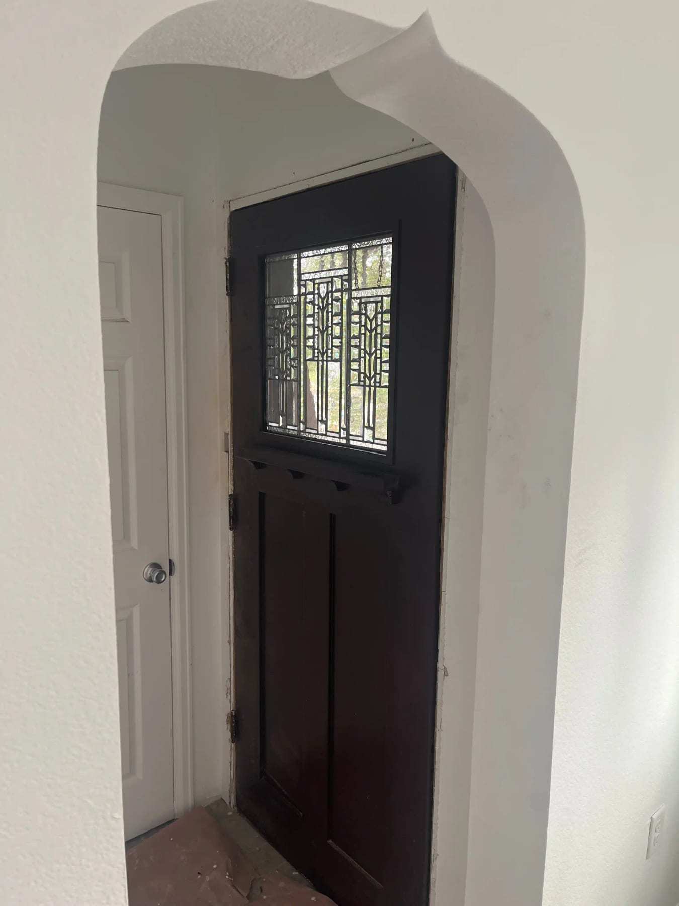 Arched entry with a dark front door and leaded glass