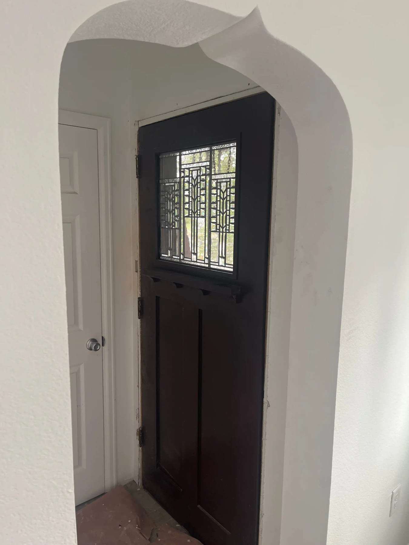 Arched entry with a dark front door and leaded glass