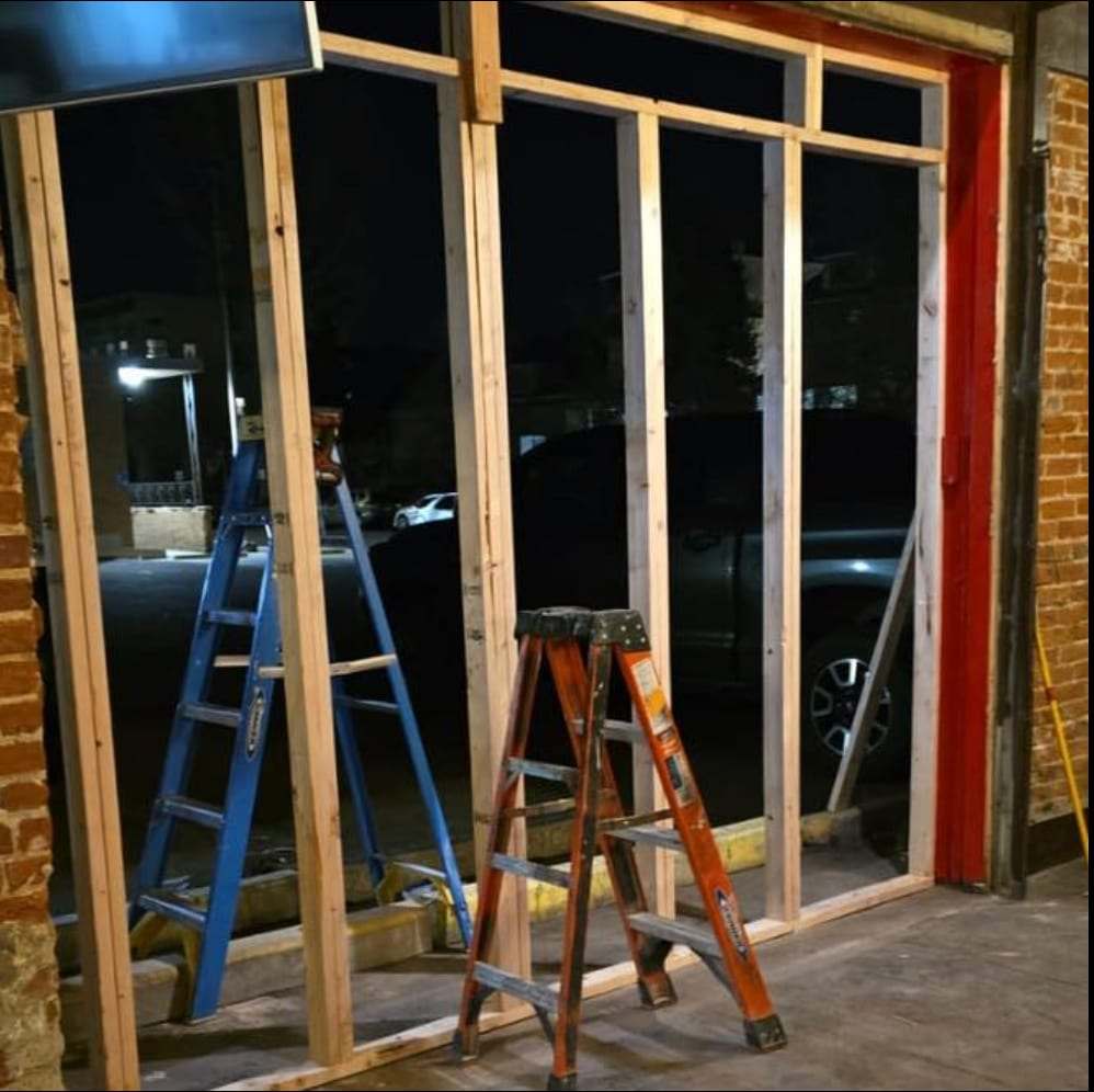 New wall framing and ladders at a storefront at night